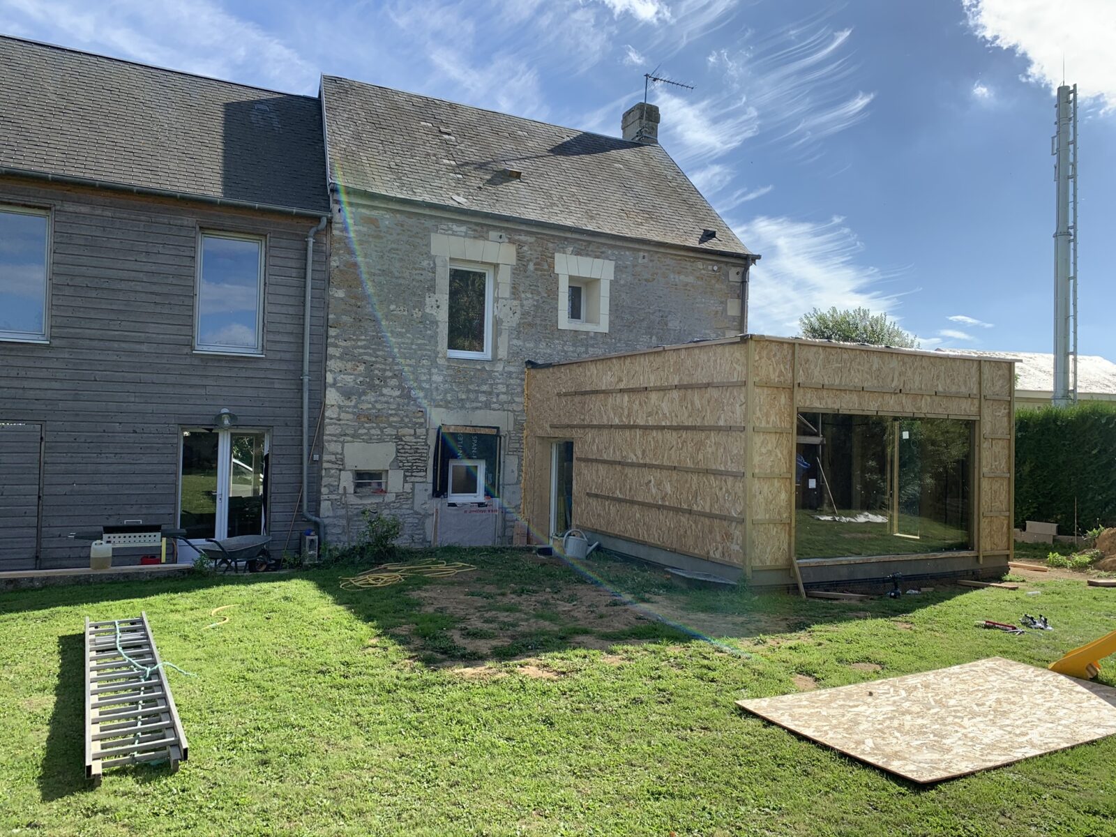 Réalisation d’une extension en ossature bois sur une maison en pierre, avec mise en place de la structure et des panneaux de contreventement.